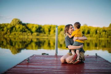 Mother and son hug each other on dock. Summer photography for a blog or advertising about family and travel