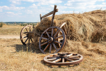 Fototapeta na wymiar Old broken wooden cart with hay. Beautiful summer day.