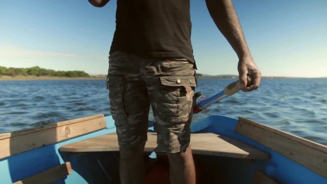 Un homme navigue debout &agrave; la barre avec sa barque sur la lagune de thau. plan serr&eacute;.
