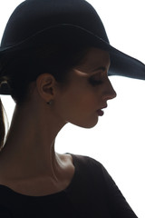 Mysterious silhouette portrait of a beautiful girl in an elegant hat with  isolated on a white background.