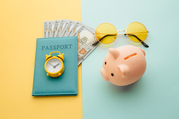 Travel accessories and piggy bank on blue yellow background. Save up for traveling.