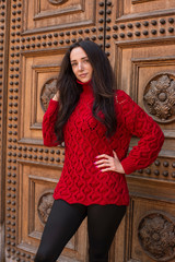 Fototapeta na wymiar Woman in red knitted sweater posing in the old city 