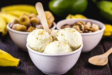 vegan banana ice cream, vegan dessert without added sugar and without milk, with fruits around. Dessert served in a biodegradable plastic pot.
