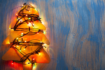Christmas tree with lights illuminated on a blue wooden background, cardboard decoration. Home made