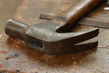 detail of the head of a carpenter's hammer on a weathered wooden table in a workshop