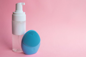 Silicone brush for washing face and cosmetic foam. Beauty and skincare concept.  Blue facial...
