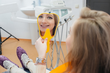 A professional dentist treats and examines the oral cavity of a pregnant girl in a modern dental office. Dentistry