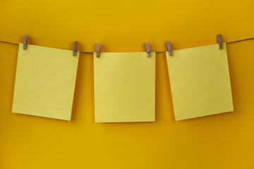 Three yellow blank sheets of paper are hanging from a rope. Memoirs. Note paper.
