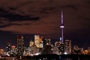 Cityscape of Toronto at night with colored CN Tower and highrise tower lights