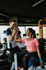 Young fit and attractive woman working out in modern gym together with her personal fitness instructor or coach.