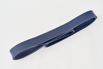 Sports equipment. Blue navy resistance band or elastic expander isolated on grey background