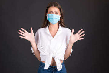 young woman with medical face mask, expressing emotions isolated on dark background