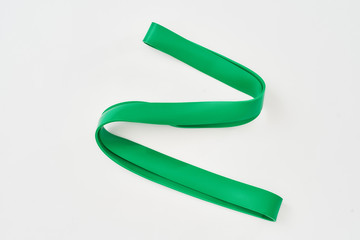 Green elastic expander. Fitness resistance band isolated on grey background