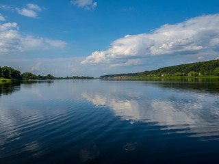 A wide river in Central Siberia. Clouds reflected in the water and beautiful shores.