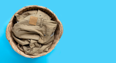Trousers in laundry basket on blue background.