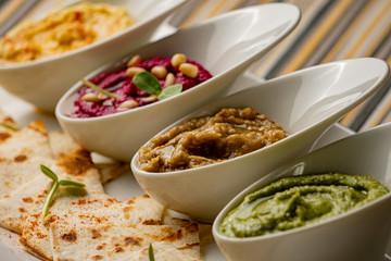 Colorful hummus bowls, healthy vegan dips. Traditional Middle eastern hummus, green hummus, beetroot hummus, spread. Assorted meze and dips with pita bread. Meze and snacks set, copy space.