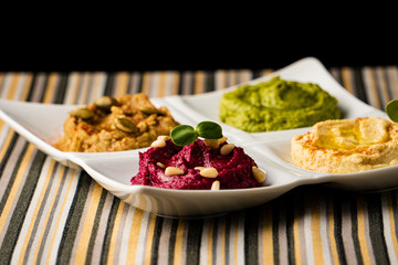 Colorful hummus bowls, healthy vegan dips. Traditional Middle eastern hummus, green hummus, beetroot hummus, spread. Assorted meze and dips with pita bread. Meze and snacks set, copy space.