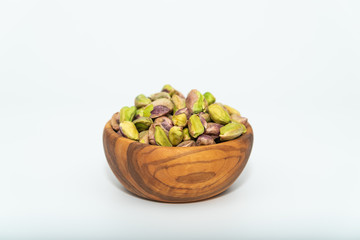 Pistachios nuts seed in a wooden bowl on white background