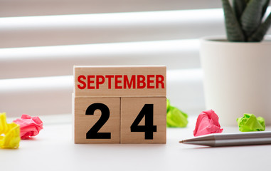 White block calendar present date 24 and month September on white wall background