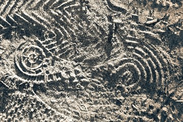 Yellow sand texture in the sunlight at sunset with traces of various shoe prints with different...