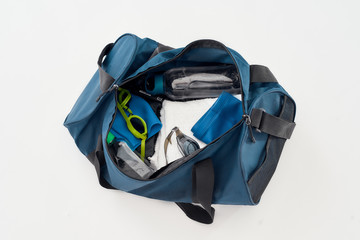 Swimming equipment. Top view of sports bag with swim goggles, hat or cap, towel and bottle of water...