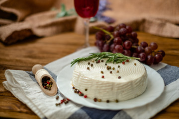 Goat cheese, grapes and wine lie on a wooden table. Cheese at home.