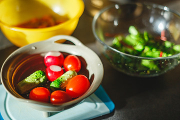 Various coloured organic vegetables washed in colander in kitchen