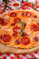 Neapolitan Pepperoni pizza with sausage, salami, cheese, rosemary and tomatoes sauce, served on a wooden board for a dinner in italian restaurant background, top view. Italy food. 