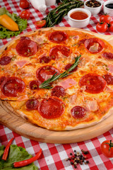 Neapolitan Pepperoni pizza with sausage, salami, cheese, rosemary and tomatoes sauce, served on a wooden board for a dinner in italian restaurant background, top view. Italy food. 