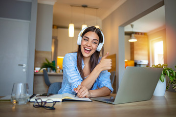 Happy girl student wear headset study online with webcam teacher write notes, happy young woman listen lecture watch webinar on laptop sit at desk, distance e learn language education concept