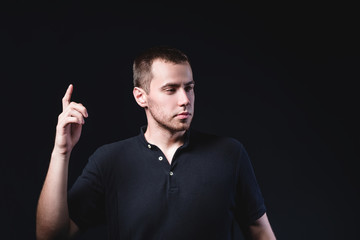 Portrait of an emotional handsome young man, on a black background in the studio, who is gesturing. Expression of emotions and feelings
