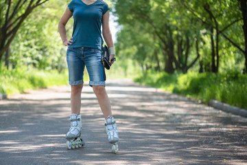 Woman on the roller skates on the park alley.