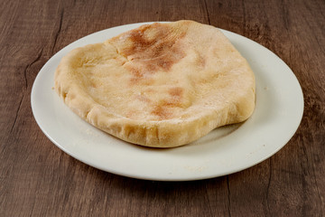pita bread or arabian bread on a white plate on a wooden board with black background