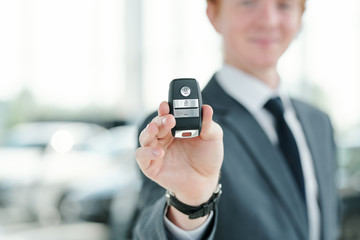 Hand of young manager or seller of vehicles holding remote control alarm system