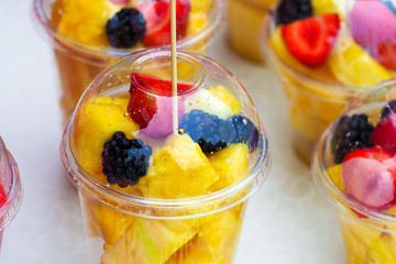Fruit salad in plastic cups. Fruit mix of melon, pineapple, strawberry, blackberry