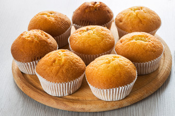 Small freshly mmuffins on a wooden table are ready to serve coffee. Sweet dessert.