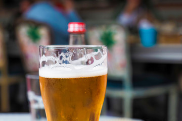 Glass with beer in pub, resting people in the background