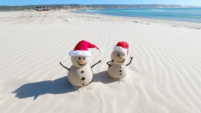 Two Sandy Christmas Snowmen are celebrating Christmas on a beautiful beach, zoom out