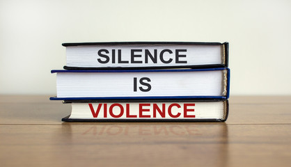 Books with text 'silence is violence' on beautiful wooden table. White background. Business concept.