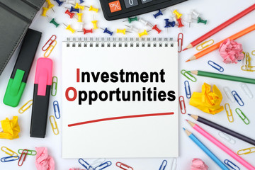 On the table is a calculator, diary, markers, pencils and a notebook with the inscription - Investment Opportunities