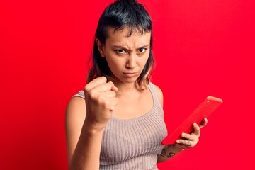 Naklejka premium Young woman holding touchpad tablet annoyed and frustrated shouting with anger, yelling crazy with anger and hand raised