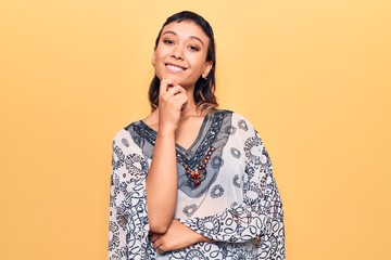 Young woman wearing casual clothes smiling looking confident at the camera with crossed arms and hand on chin. thinking positive.