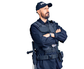 Young handsome man wearing police uniform looking to the side with arms crossed convinced and confident