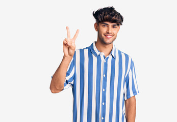 Young hispanic man wearing casual clothes showing and pointing up with fingers number two while smiling confident and happy.