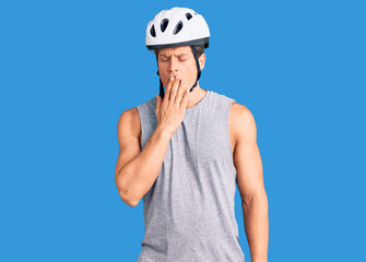 Young handsome man wearing bike helmet bored yawning tired covering mouth with hand. restless and sleepiness.
