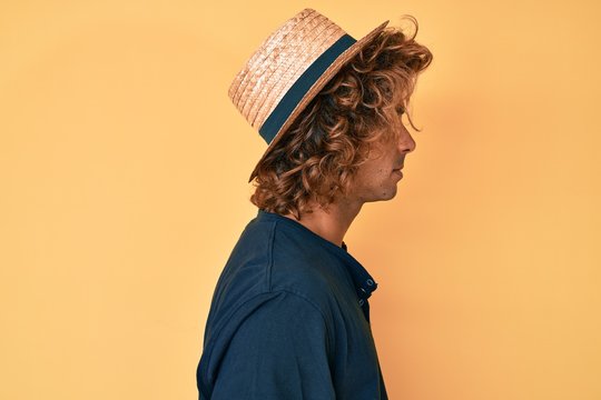 Young hispanic man wearing summer hat looking to side, relax profile pose with natural face with confident smile.