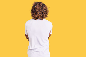 Young hispanic man wearing casual white tshirt standing backwards looking away with crossed arms