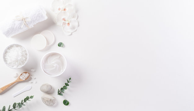 Cosmetic bottle containers, skin cream with flowers. Natural beauty and spa concept, Top view on white table background.