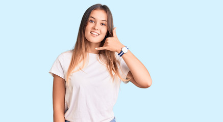 Fototapeta premium Beautiful caucasian woman wearing casual white tshirt smiling doing phone gesture with hand and fingers like talking on the telephone. communicating concepts.