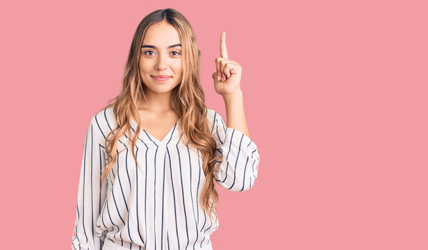 Young beautiful blonde woman wearing casual clothes pointing finger up with successful idea. exited and happy. number one.